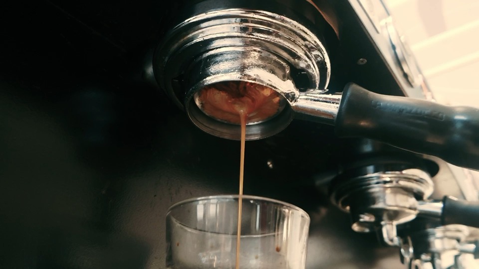 Espresso pouring from a bottomless portafilter into a glass.
